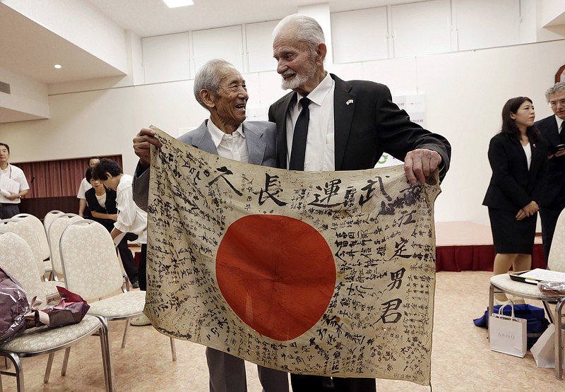 
              WWII veteran Marvin Strombo, right, and Tatsuya Yasue, 89-year-old farmer, hold a Japanese flag with autographed messages which was owned by his brother Sadao Yasue, who was killed in the Pacific during World Work II, during a ceremony in Higashishirakawa, in central Japan's Gifu prefecture Tuesday, Aug. 15, 2017. Strombo has returned to the fallen soldier's family the calligraphy-covered flag he took from the man's body 73 years ago. (AP Photo/Eugene Hoshiko)
            