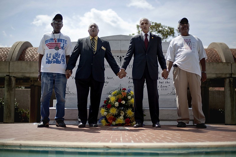 
              FILE - In this Wednesday, April 4, 2012 file photo, civil rights activists and Southern Christian Leadership Conference members from left, Ralph Worrell, Dr. Bernard Lafayette, Jr., C.T. Vivian and Frederick Moore, join hands and sing "We Shall Overcome" at the Atlanta gravesite of Rev. Martin Luther King Jr., marking the 44th anniversary of his assassination. Lafayette fought to end segregation during the Civil Rights Movement. But watching the events of Charlottesville, Va., in August 2017 and days later hearing President Donald Trump blaming both sides for the deadly violence, Lafayette realized that his work to change laws has not changed enough hearts and minds in America. (AP Photo/David Goldman)
            