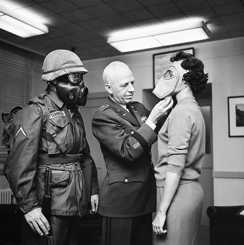 
              FILE - In this Jan. 19, 1959 file photo, Pfc. Warner Bitterman, left, watches as Army chief chemical officer Maj. Gen. Marshall Stubbs, center, checks new civilian gas mask being worn secretary Margaret Francis at his Pentagon office in Washington. For some baby boomers, North Korea's nuclear advances and the Trump administration's bellicose response have prompted flashbacks to a time when they were young, and when they prayed each night that they might awaken the next morning. For their children, the North Korean crisis was a taste of what the Cold War was like. (AP Photo, File)
            