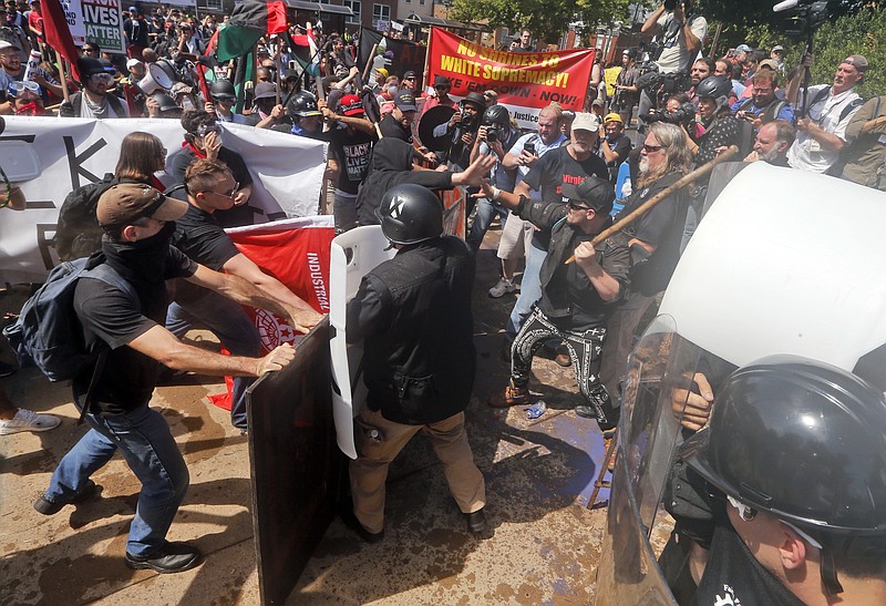 
              In this Saturday, Aug. 12, 2017, photo, white nationalist demonstrators clash with counter demonstrators at the entrance to Lee Park in Charlottesville, Va. President Donald Trump on Aug. 15, defended his response to Saturday’s racially-charged protests in Charlottesville in a winding, combative exchange with reporters that at times mischaracterized the message and purpose of event. In his remarks, Trump described the rally as largely a debate over removal of a Confederate monument, although organizers billed the rally as push back against the “anti-white climate.” Trump also misstated his levels of political support in the 2016 election. (AP Photo/Steve Helber)
            
