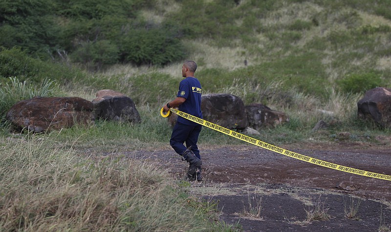 
              A Honolulu firefighter stretches caution tape across the entrance of Kaena Point, Wednesday, Aug. 16, 2017 in Mokuleia, Hawaii. An Army helicopter with five on board crashed several miles off Oahu's North Shore late Tuesday. Rescue crews are searching the waters early Wednesday. (AP Photo/Marco Garcia)
            