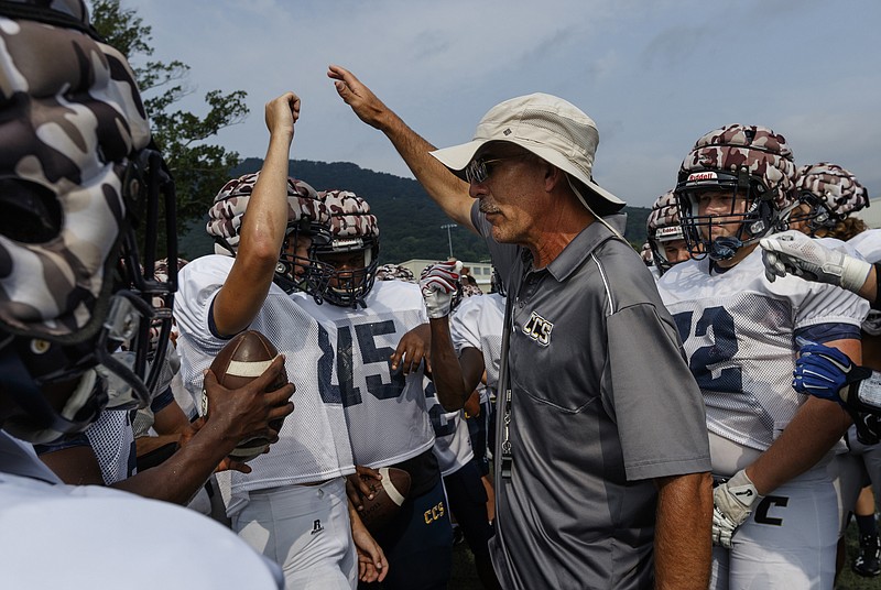 Coach Mark Mariakis talks to his team, who are wearing "guardian caps" over their helmets, during the Chargers' football scrimmage at Chattanooga Christian School on Thursday, July 27, 2017, in Chattanooga, Tenn. Guardian caps, which are used to mitigate the effects of concussions and blows to the head in football, are seeing increased use as concerns about head injuries in the sport rise.