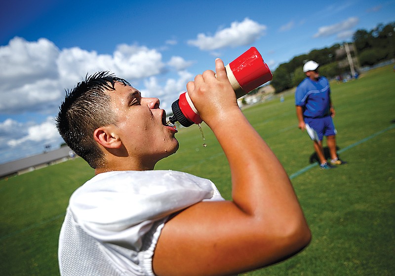 Abraham Reyes takes a drink during football practice.
