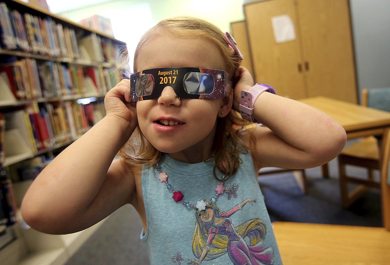 
              FILE - In this Wednesday, Aug. 2, 2017 file photo, Emmalyn Johnson, 3, tries on her free pair of eclipse glasses at Mauney Memorial Library in Kings Mountain, N.C. Glasses are being given away at the library for free while supplies last ahead of the big event on Aug. 21. (Brittany Randolph/The Star via AP)
            