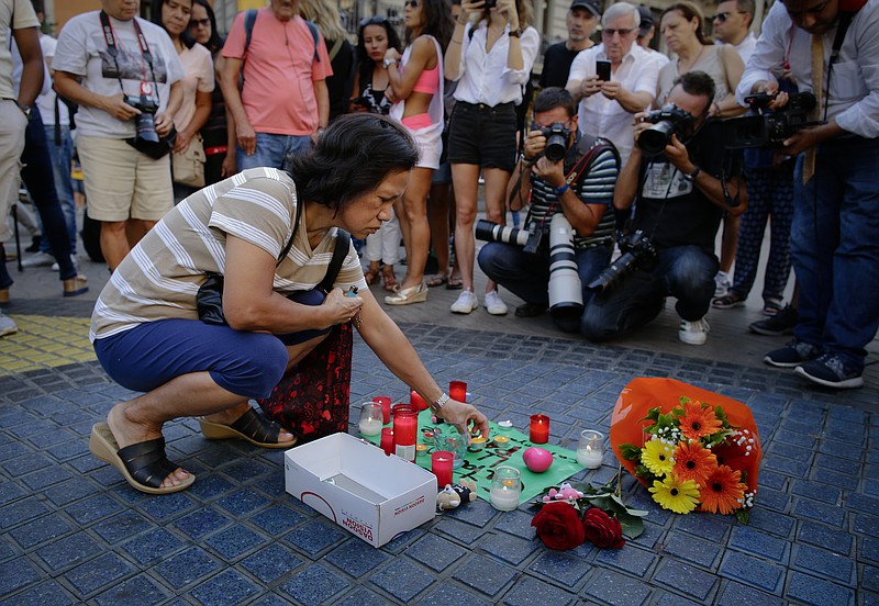 
              A woman places a candle on a paper that reads "Catalunya - place of peace" in Las Ramblas, Barcelona, Spain, Friday, Aug. 18, 2017. Spanish police on Friday shot and killed five people carrying bomb belts who were connected to the Barcelona van attack that killed at least 13, as the manhunt intensified for the perpetrators of Europe's latest rampage claimed by the Islamic State group. (AP Photo/Manu Fernandez)
            