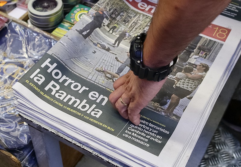 
              A man touches a newspaper displaying a photograph of the aftermath of the terror attack in Las Ramblas, in Barcelona, Spain, Friday, Aug. 18, 2017. A white van jumped up onto a sidewalk and sped down a pedestrian zone Thursday in Barcelona's historic Las Ramblas district, swerving from side to side as it plowed into tourists and residents. Police said 13 people were killed and more than 50 wounded in what they called a terror attack.(AP Photo/Manu Fernandez)
            