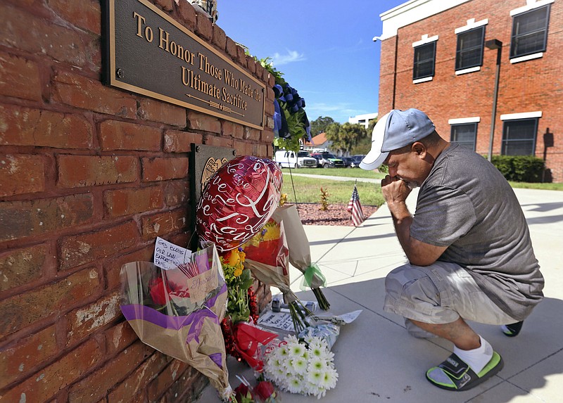 
              CORRECTS STATUS OF SECOND POLICE OFFICER - After placing flowers at a makeshift memorial, Miguel Velez, say's a prayer for the officer that was killed on Saturday, Aug. 19, 2017 in Kissimmee, Fla.   The Kissimmee Police Department says Sgt. Sam Howard died Saturday from his injuries. His colleague, Officer Matthew Baxter, died Friday night after the attack in a neighborhood of Kissimmee, located south of the theme park hub of Orlando.   (Red Huber/Orlando Sentinel via AP)
            