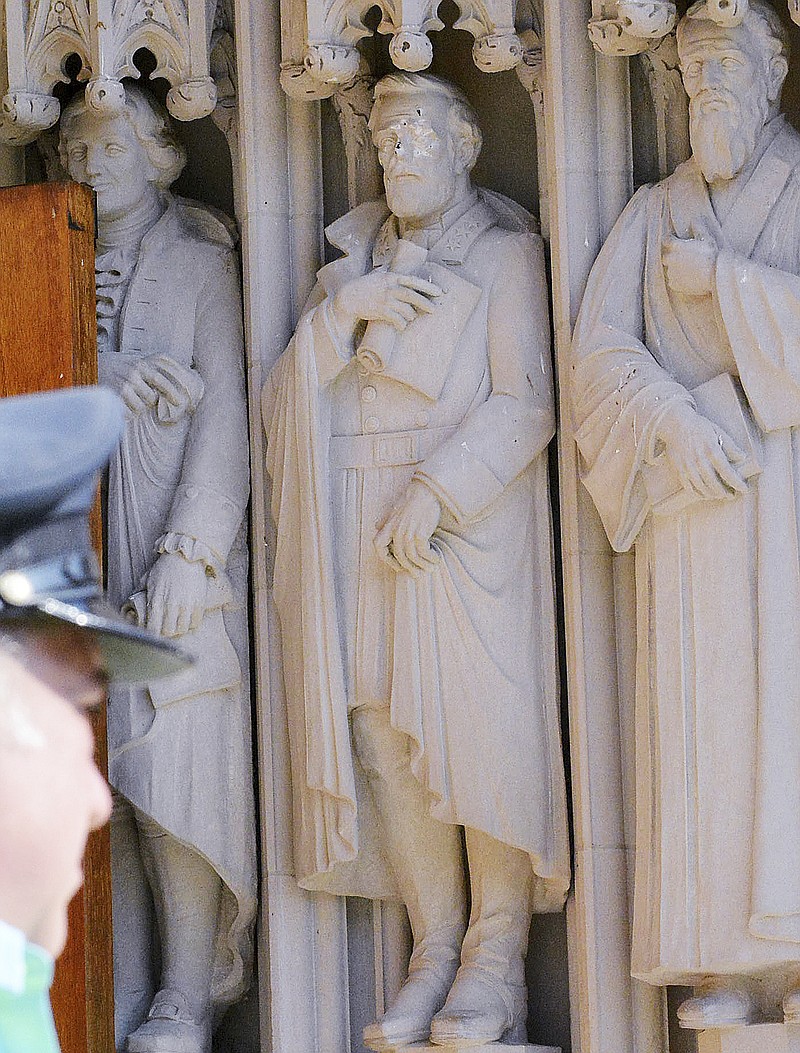 
              FILE - In this Aug. 17, 2017 file photo, the defaced Gen. Robert E. Lee statue, center, stands at the Duke Chapel in Durham, N.C. Duke  Duke University removed a statue of Gen. Robert E. Lee early Saturday, Aug. 19, days after it was vandalized amid a national debate about monuments to the Confederacy.  The university said it removed the carved limestone likeness early Saturday morning from Duke Chapel where it stood among 10 historical figures depicted in the entryway  (Bernard Thomas/The Herald-Sun via AP, File)
            