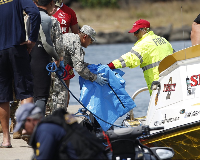
              Water safety officials hand over possible debris from an Army UH-60 Black Hawk helicopter crash to military personnel stationed at a command center in a harbor, Wednesday, August 16, 2017 in Haleiwa, HI. An Army helicopter with five on board crashed several miles off Oahu's North Shore late Tuesday. Officials have suspended the search for five Army soldiers in a helicopter crash during offshore training in Hawaii on Monday, Aug. 21, 2017. (AP Photo/Marco Garcia, File)
            