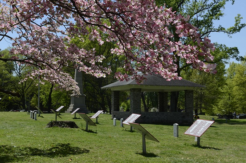 Framed by a blooming dogwood tree, historical markers list the names of some of the Confederate dead buried in a mass grave at the Chattanooga Confederate Cemetery.