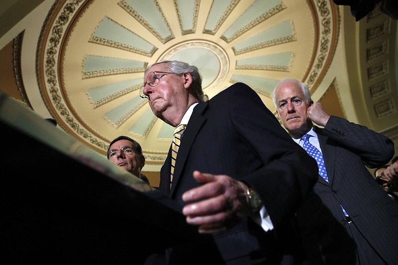 FILE - In this July 25, 2017 file photo, Senate Majority Leader Mitch McConnell of Ky., center, with Senate Majority Whip John Cornyn of Texas, right, and Sen. John Barrasso, R-Wyo., talks to reporters on Capitol Hill in Washington. (AP Photo/Jacquelyn Martin, File)