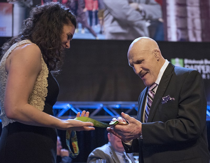 
              FILE – In this Feb. 15, 2017, file photo, retired professional wrestler Bruno Sammartino examines U.S. rower Amanda Polk's Olympic gold medal at the 81st Dapper Dan Awards and sports auction, a fundraiser for the Boys & Girls Clubs of Western Pennsylvania, in Pittsburgh. Sammartino met with pop singing sensation Bruno Mars on Tuesday, Aug. 22, 2017, when Mars' 24K Magic World Tour stopped in Pittsburgh, after Sammartino heard Mars was nicknamed "Bruno" as a baby because Sammartino was Mars' father's favorite wrestler. (Haley Nelson/Pittsburgh Post-Gazette via AP, File)
            