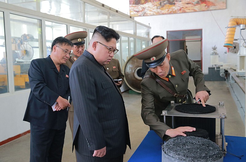 
              In this undated photo distributed Wednesday, Aug. 23, 2017, by the North Korean government, leader Kim Jong Un, center, visits the Chemical Material Institute of Academy of Defense Science at an undisclosed location in North Korea. North Korea's state media released photos Wednesday that appear to show the designs of one or possibly two new missiles.  Concept diagrams of the missiles were seen hanging on a wall behind leader Kim Jong Un while he visited a plant that makes solid-fuel engines for the country's ballistic-missile program.Independent journalists were not given access to cover the event depicted in this photo. (Korean Central News Agency/Korea News Service via AP)
            