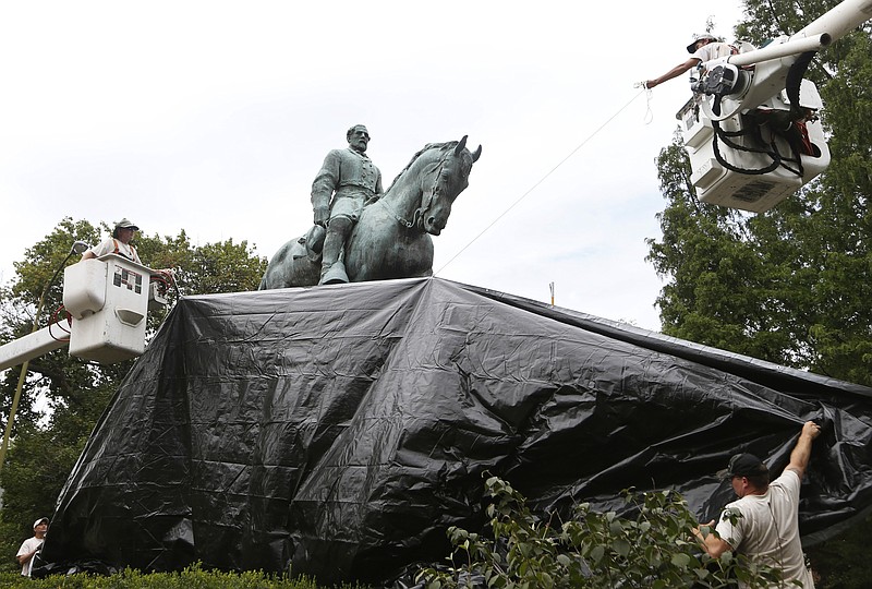 
              City workers drape a tarp over the statue of Confederate General Robert E. Lee in Emancipation park in Charlottesville, Va., Wednesday, Aug. 23, 2017.  The move to cover the statues is intended to symbolize the city's mourning for Heather Heyer, killed while protesting a white nationalist rally earlier this month.  (AP Photo/Steve Helber)
            