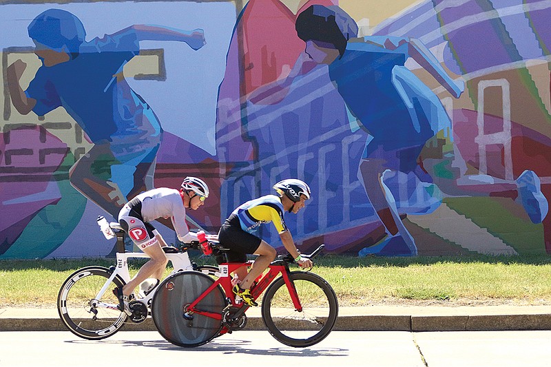 Staff Photo by Dan Henry / The Chattanooga Times Free Press- 9/25/16. Adam Weeks #2143, from Hickory, NC, and TinTin Rexach #437, from San Juan, PR, ride past a run mural while on the bike course during the 2016 Little Debbie IRONMAN Chattanooga triathlon on September 25, 2016. More than 2,700 athletes registered to compete in a 2.4-mile swim, 116-mile bike and 26.2-mile run throughout Chattanooga and North Georgia. 
