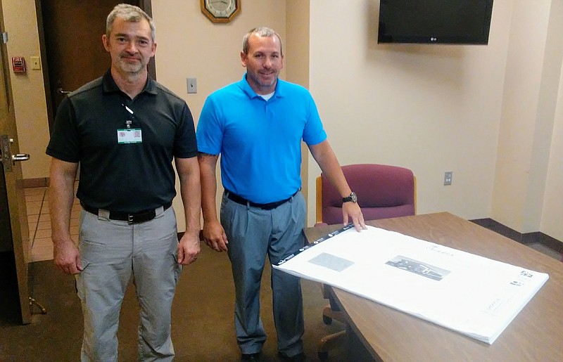 Kenny Custer, East Ridge's chief building and fire code official (right) and Building Inspector Michael Howell stand near the inch-thick plans for a new Chick-fil-A in East Ridge near Exit 1 on I-75.