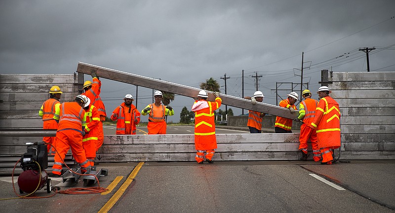 TxDOT crews install the final portion of a surge wall on TX-361 leading to the Port Aransas ferry in Aransas Pass, Texas, on Friday, Aug. 25, 2017. Conditions deteriorated Friday along the Texas Gulf Coast as Hurricane Harvey strengthened and crawled toward the state, with forecasters warning that evacuations and preparations "should be rushed to completion." (Nick Wagner /Austin American-Statesman via AP)

