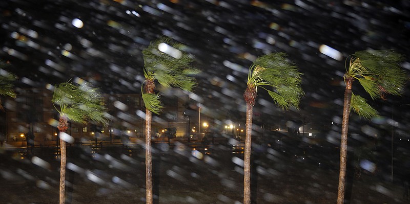 Rain is blown past palm trees as Hurricane Harvey makes landfall, Friday, Aug. 25, 2017, in Corpus Christi, Texas. Harvey intensified into a hurricane Thursday and steered for the Texas coast with the potential for up to 3 feet of rain, 125 mph winds and 12-foot storm surges in what could be the fiercest hurricane to hit the United States in almost a dozen years. (AP Photo/Eric Gay)