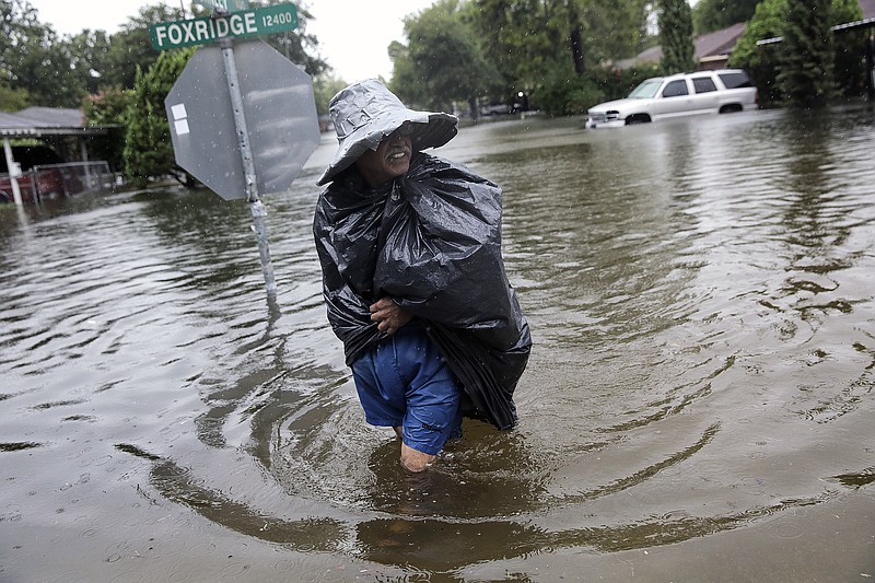 
              A Melrose Place neighbor wears makeshift rain gear as he walks the flooded streets to check on his Houston neighbors as Tropical Storm Harvey makes its way through the area on Monday, Aug. 28, 2017. (Elizabeth Conley/Houston Chronicle via AP)
            