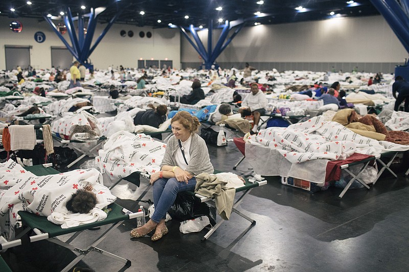 Susie Williams, a volunteer from Memphis, Tenn., speaks with a young girl at a temporary shelter at the George R. Brown Convention Center in downtown Houston on Sunday.