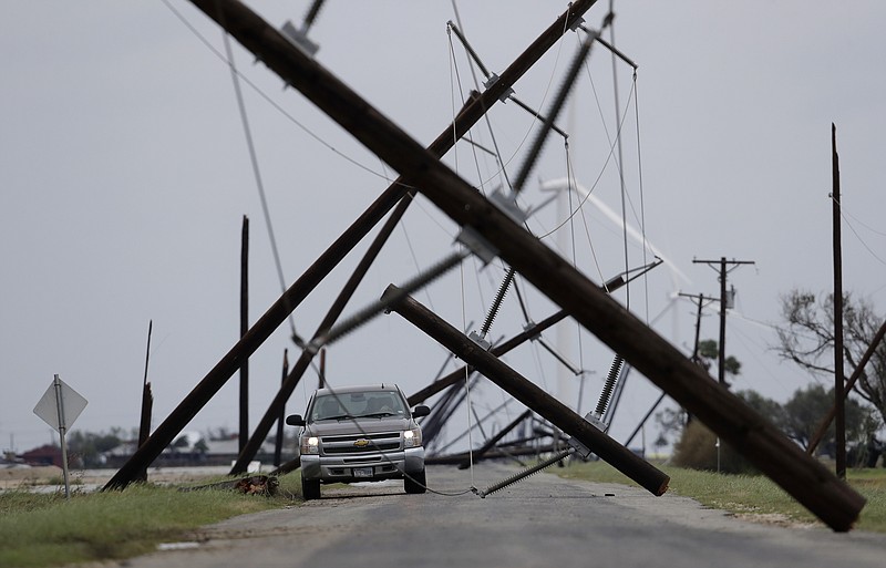 A driver works his way through a maze of fallen utility poles damaged in the wake of Hurricane Harvey, Saturday, Aug. 26, 2017, in Taft, Texas. (AP Photo/Eric Gay)