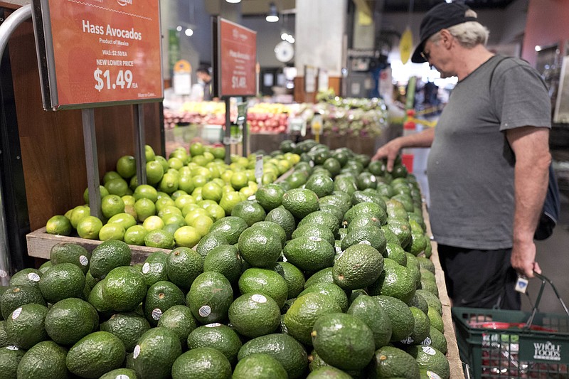 A man shops for avocados at a Whole Foods Market, Monday, Aug. 28, 2017, in New York. Amazon is moving swiftly to make big changes at Whole Foods, saying it plans to cut prices on avocados, bananas, eggs, salmon, beef and more. Amazon has completed its $13.7 billion takeover of organic grocer Whole Foods, and the e-commerce giant is wasting no time putting its stamp on the company. (AP Photo/Mark Lennihan)