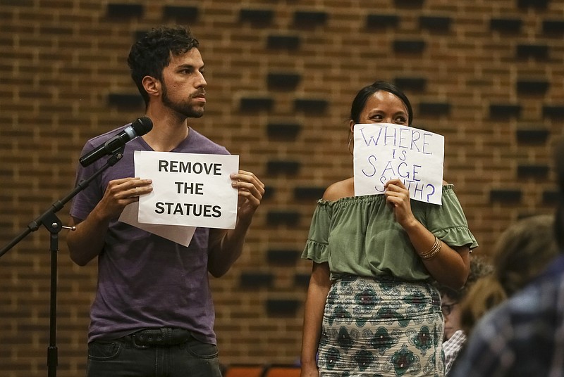 
              In this Sunday, Aug. 27, 2017 photo, two community members hold up signs as they speak to a crowd in the Martin Luther King Jr. Performing Arts Center during a community meeting organized by the Department of Justice's Community Relations Service in Charlottesville, Va. Charlottesville residents told city leaders at an emotional community meeting they were traumatized by a white nationalist rally and dissatisfied with the way officials handled the event and the violence that unfolded. (Zack Wajsgras/The Daily Progress via AP)
            