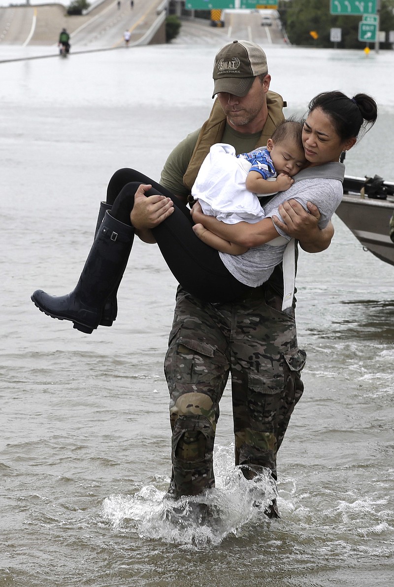 
              Houston Police SWAT officer Daryl Hudeck carries Catherine Pham and her 13-month-old son Aiden after rescuing them from their home surrounded by floodwaters from Tropical Storm Harvey Sunday, Aug. 27, 2017, in Houston. (AP Photo/David J. Phillip)
            