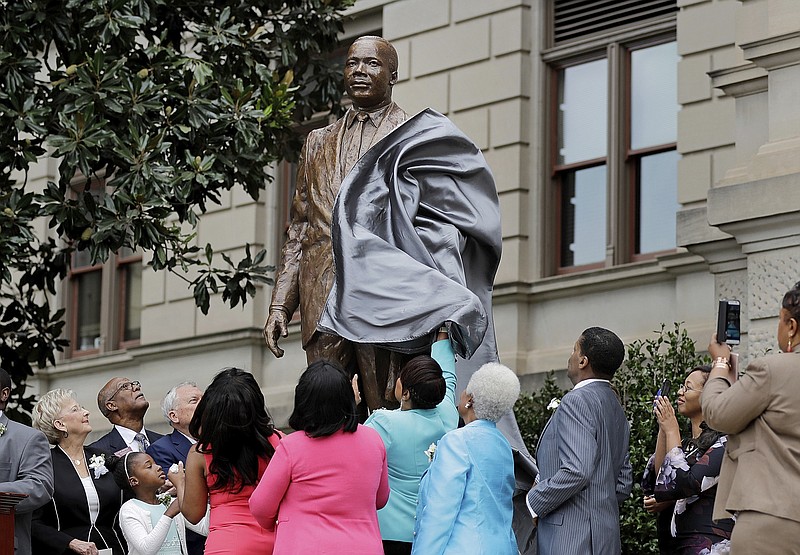 A statue paying tribute to civil rights leader Martin Luther King Jr. is unveiled on the state Capitol grounds in Atlanta, Monday, Aug. 28, 2017. The statue's unveiling Monday came more than three years after Georgia lawmakers endorsed the project. A replica of the nation's Liberty Bell tolled three times before the 8-foot (2.44-meter) bronze statue was unveiled on the 54th anniversary of King's "I have a dream" speech at the march on Washington. (AP Photo/David Goldman)