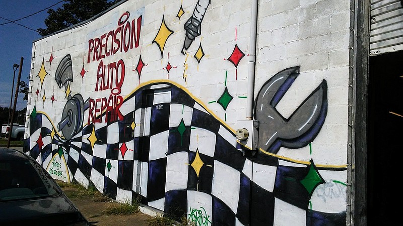 Muralist Jackson Hendrickson spray-painted a giant piston, spark plug and wrench above a black-and-white checkered race flag at Precision Auto Repair at 4406 Rossville Blvd.