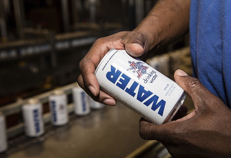 
              In this undated photo provided by Anheuser-Busch a man shows a canned water in Cartersville, Ga. The brewery is shipping canned drinking water to the American Red Cross to help Hurricane Harvey relief efforts in Texas and Louisiana. (Anheuser-Busch via AP)
            