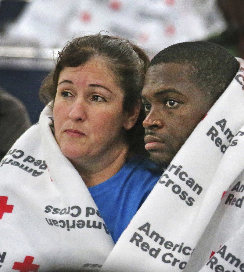 Displaced South Houston residents Oralia Guerra and Diamond Robinson huddle together to stay warm underneath Red Cross blankets at the George Brown Convention Center in Houston on Monday, Aug. 28, 2017, in the wake of Tropical Storm Harvey. Floodwaters reached the rooflines of single-story homes Monday and people could be heard pleading for help from inside as Harvey poured rain on the Houston area for a fourth consecutive day after a chaotic weekend of rising water and rescues. (Louis DeLuca/The Dallas Morning News via AP)
