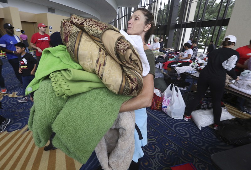 Volunteer Judy Segar carries donated blankets for victims of the flooding from Tropical Storm Harvey at a shelter opened at the Lakewood Church in Houston, Texas, Tuesday, Aug. 29, 2017. (AP Photo/LM Otero)