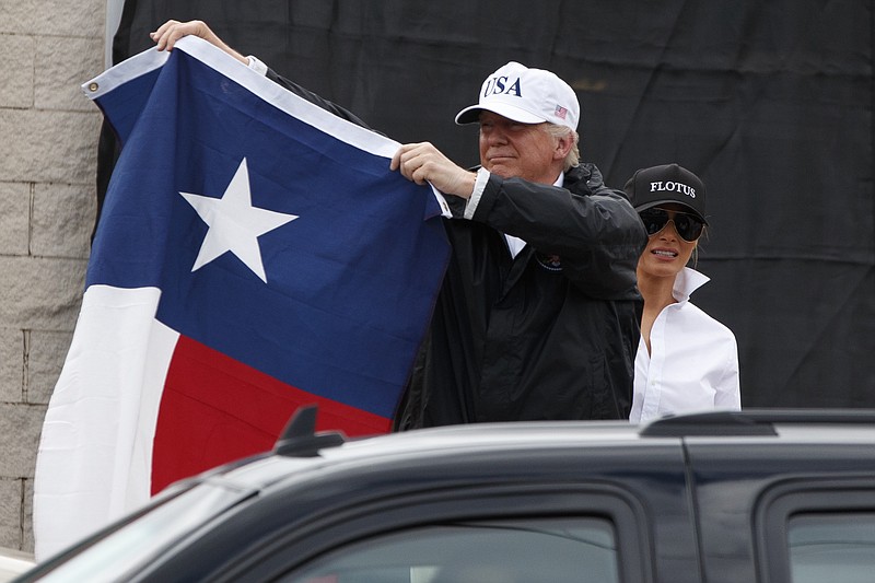 
              President Donald Trump, accompanied by first lady Melania Trump, holds up a Texas flag after speaking with supporters outside Firehouse 5 in Corpus Christi, Texas, uesday, Aug. 29, 2017, , where he received a briefing on Harvey relief efforts. (AP Photo/Evan Vucci)
            