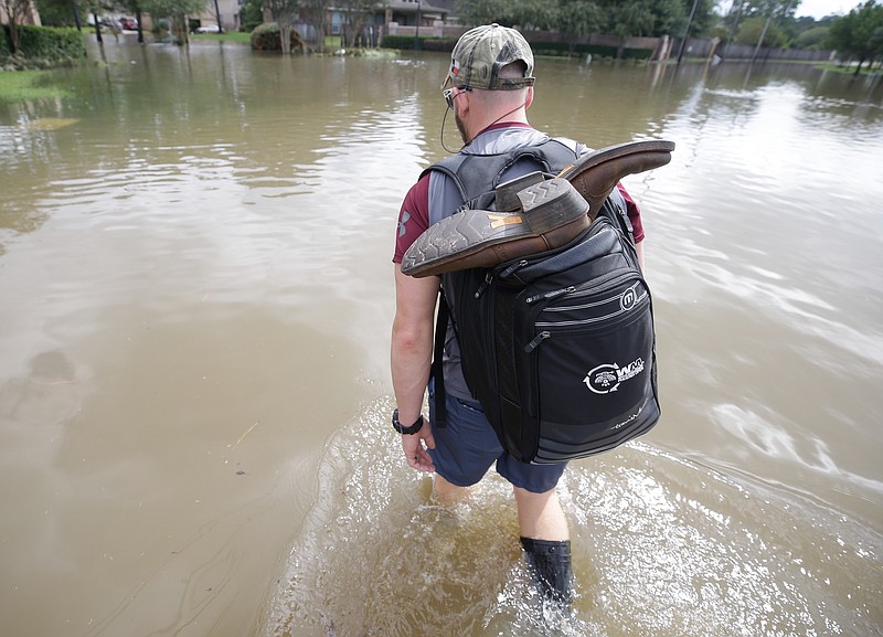 
              CORRECTS CREDIT - Danny Hannon carries his dry boots in his backpack as he goes to check his home in the aftermath of Harvey, Wednesday, Aug. 30, 2017 in Houston. Harvey's floodwaters started dropping across much of the Houston area, but many thousands of homes in and around the nation's fourth-largest city were still swamped and could stay that way for days or longer. (Melissa Phillip/Houston Chronicle via AP)
            