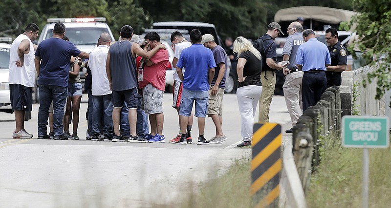 Family members react as a van is pulled out of the Greens Bayou with the bodies of six family members on Wednesday, Aug. 30, 2017, in Houston. The van was carried into the bayou during Tropical Storm Harvey as the water went over the bridge. ( Elizabeth Conley/Houston Chronicle via AP)