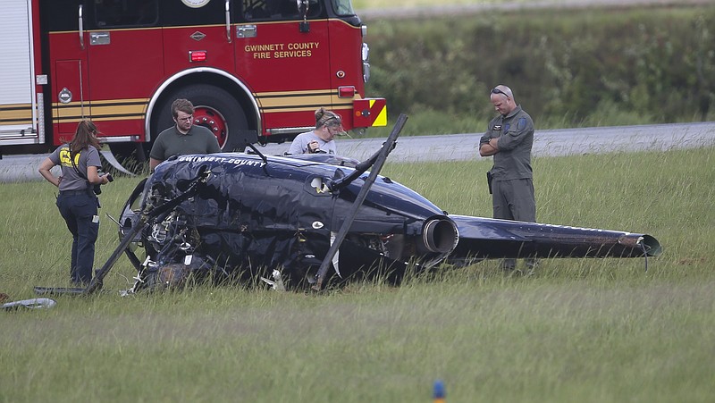 Investigators look over the wreckage of a Gwinnett County Police helicopter that crashed at the Gwinnett County Airport in Lawrenceville, Ga., on Friday, Sept. 1, 2017. The two officers onboard were taken to a local hospital for treatment. (AP Photo/John Bazemore)

