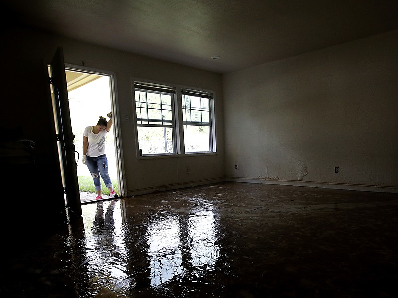 
              FILE - In this Aug. 31, 2017 file photo, Alejandra Castillo takes a break from carrying water-soaked items out of her family's home after flood waters receded in Houston. Experts say Harvey’s filthy floodwaters pose significant dangers to human safety and the environment that will remain even after levels drop far enough that southeastern Texas residents no longer fear for their lives. (AP Photo/Charlie Riedel, File)
            