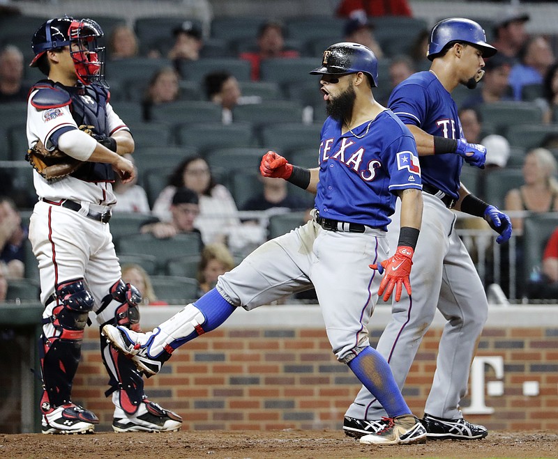 Texas Rangers' Rougned Odor, center, celebrates after hitting a two-run home run to score teammate Carlos Gomez, right, as Atlanta Braves catcher Kurt Suzuki, left, looks on in the fifth inning of a baseball game in Atlanta, Monday, Sept. 4, 2017. (AP Photo/David Goldman)