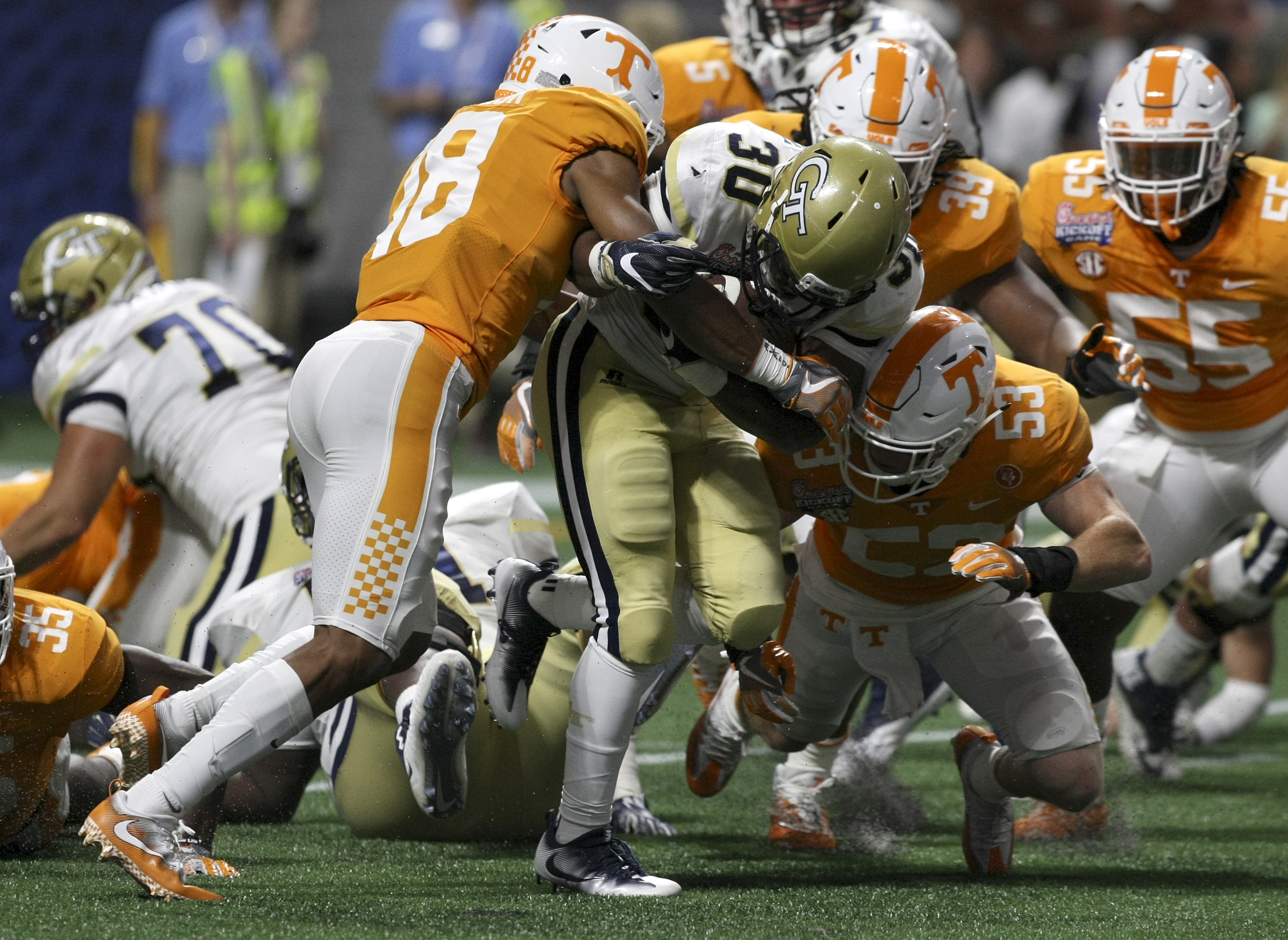 Tennessee defensive back Nigel Warrior (18) and linebacker Colton Jumper (53) tackle Georgia Tech running back KirVonte Benson (30) during the Chick-fil-A Kickoff Game at Mercedes-Benz Stadium on Monday, Sept. 4, in Atlanta, Ga.