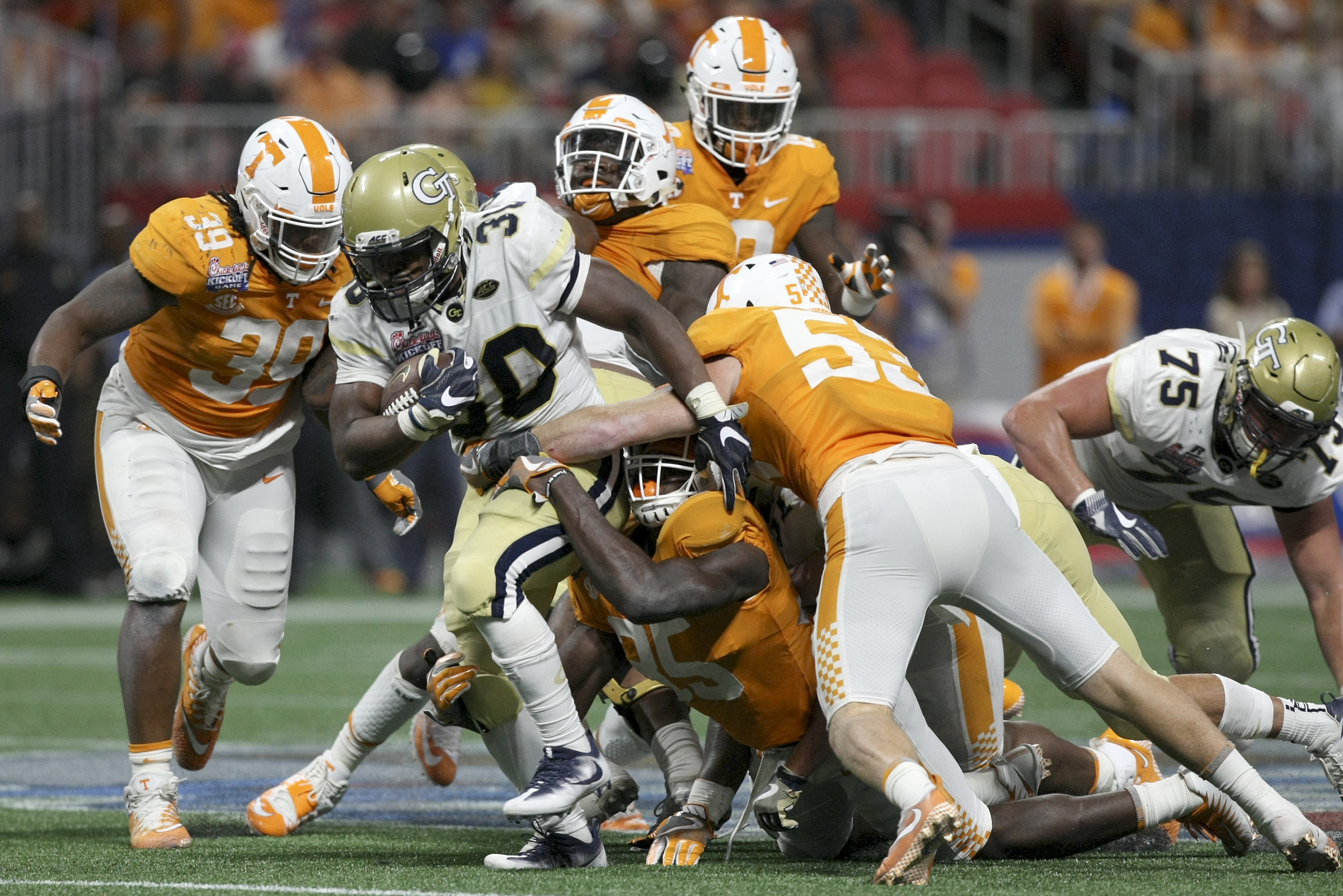 Georgia Tech running back KirVonte Benson (30) fights for extra yardage against Tennessee linebackers Colton Jumper (53) and Daniel Bituli (35) during the Chick-fil-A Kickoff Game at Mercedes-Benz Stadium on Monday, Sept. 4, in Atlanta, Ga.