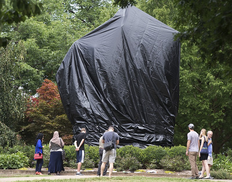 
              FILE - In this Wednesday, Aug. 23, 2017 file photo, people look at the covered statue of Confederate Gen. Robert E. Lee in Emancipation Park in Charlottesville, Va. The move to cover the statues was intended to symbolize the city's mourning for Heather Heyer, killed while protesting a white nationalist rally earlier in the month. (AP Photo/Steve Helber)
            