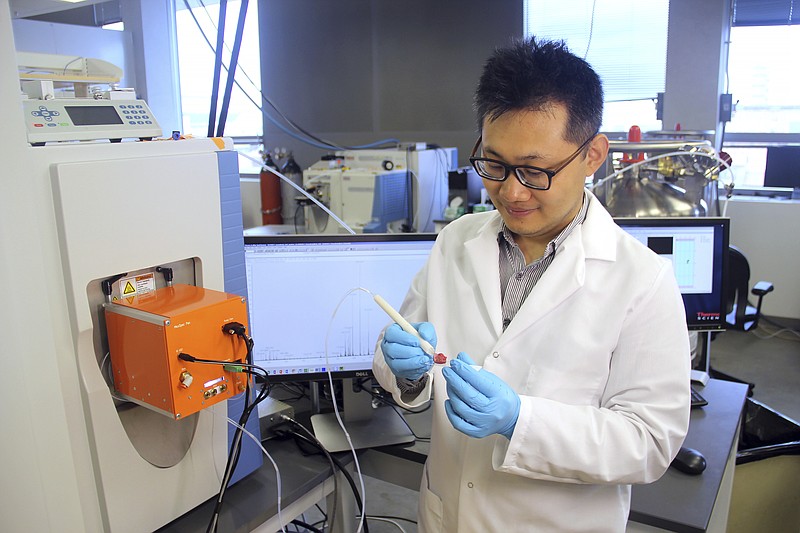 
              This photo provided by the University of Texas at Austin, shows scientist Jialing Zhang as he demonstrates using the MasSpec Pen to analyze a human tissue sample.  Scientists are developing a highly experimental pen-like probe to help surgeons better tell when it's safe to stop cutting or if stray tumor cells still lurk. (University of Texas at Austin via AP)
            