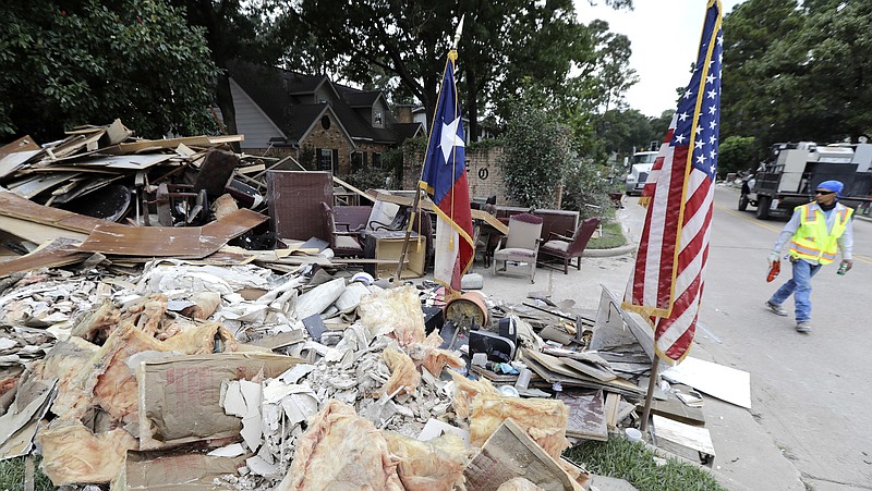 
              In this Sept. 5, 2017, photo, a worker walks past a pile of debris outside a business damaged by floodwaters in the aftermath of Hurricane Harvey in Spring, Texas. With federal disaster reserves running out, the House is swiftly moving to pass President Donald Trump’s request for a $7.9 billion first installment of relief for victims of Harvey. GOP leaders also hope to use the urgent Harvey aid bill to solve a far more vexing issue: Increasing the U.S. debt limit to permit the government to borrow freely again to cover its bills.  (AP Photo/David J. Phillip)
            