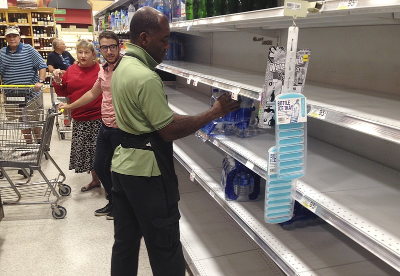 
              An employee restocks bottled water on bare shelves as customers look on at a Publix grocery store, Tuesday, Sept. 5, 2017, in Surfside, Fla. Wielding the most powerful winds ever recorded for a storm in the Atlantic Ocean, Hurricane Irma bore down Tuesday on the Leeward Islands of the northeast Caribbean on a forecast path that could take it toward Florida over the weekend. (AP Photo/Wilfredo Lee)
            