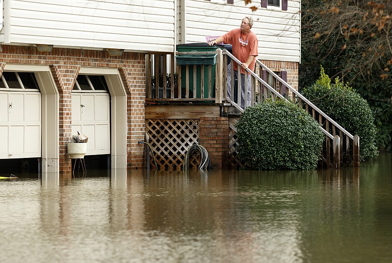 Rex Wheeler, who spent Saturday moving belongings above the floodwaters in his basement, looks out from his front porch after Christmas day rainfall brought South Chickamauga Creek to a flood stage of about 26.5 feet on Sunday, Dec. 27, 2015, in East Ridge, Tenn. Major flood stage classification for the creek is 27 feet.