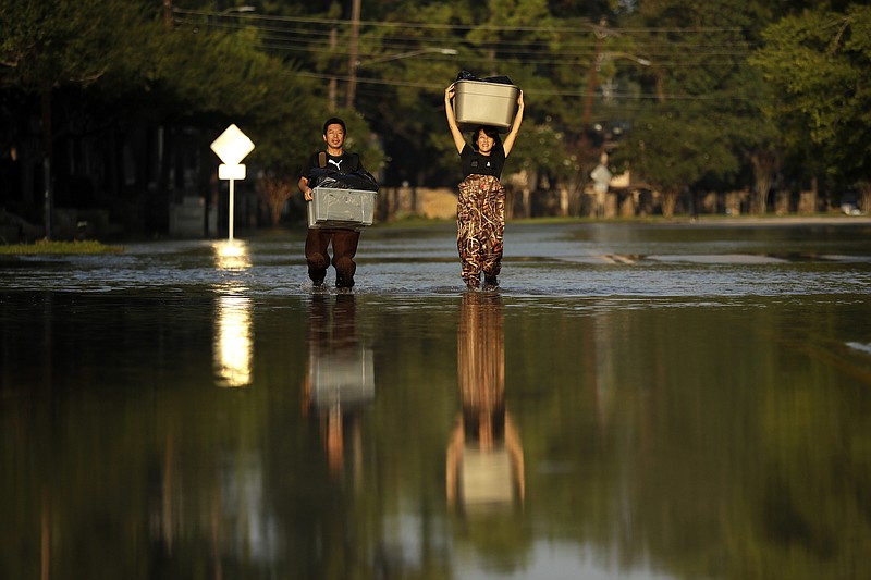 Mariko Shimmi, right, helps carry items out of the home of Ken Tani in a neighborhood still flooded from Harvey on Monday, Sept. 4, 2017, in Houston. Some neighborhoods around Houston remain flooded and thousands of people have been displaced by torrential rains and catastrophic flooding since Harvey slammed into Southeast Texas last week. (AP Photo/Gregory Bull)