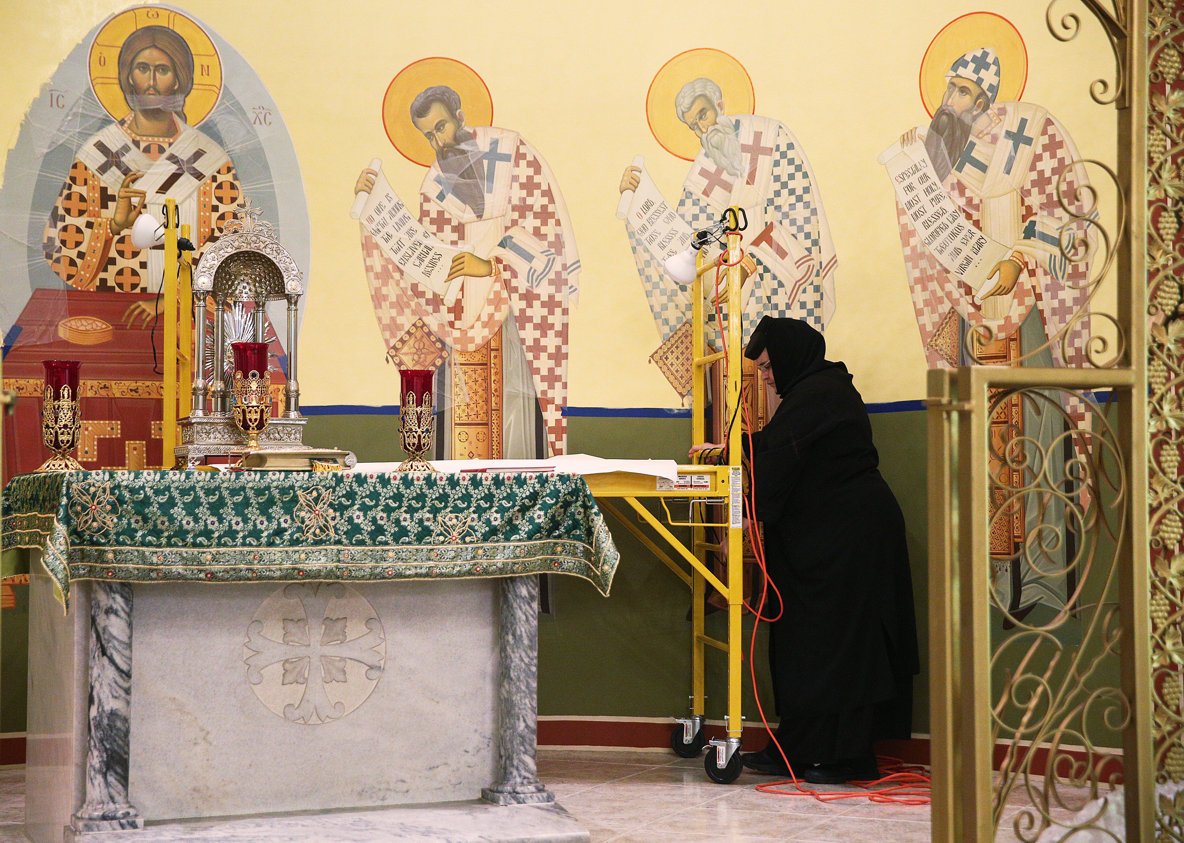 Mother Teodora Balaban moves scaffolding to reach an area of the altar iconography along the wall Thursday, Aug. 24, 2017, at Annunciation Greek Orthodox Church in Chattanooga, Tenn. Balaban's task was to finish the altar iconography that was actually begun in 1979 by her mentor and teacher Alias Katsaros.