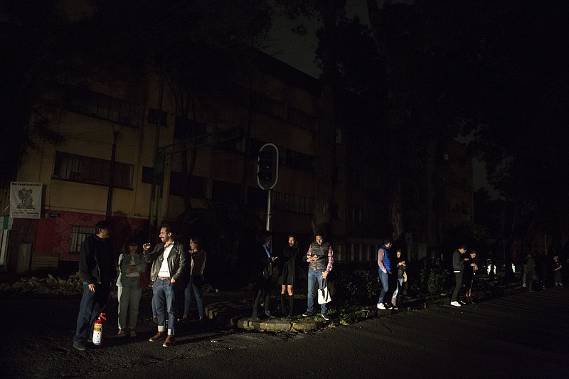 
              People who evacuated from bars during an earthquake stand in the street in La Roma neighborhood of Mexico City, sections of which lost power, just before midnight on Thursday, Sept. 7, 2017. A massive earthquake hit off the coast of southern Mexico late Thursday night, causing buildings to sway violently and people to flee into o the streets in panic as far away as the capital city. (AP Photo/Rebecca Blackwell)
            