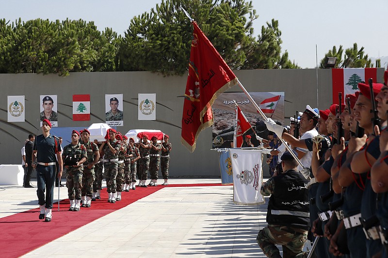 
              Lebanese army soldiers carry coffins wrapped in Lebanese national flag of eight Lebanese soldiers who were abducted in 2014 and later killed by Islamic State militants, at the Lebanese Defense Ministry in Yarzeh, near Beirut, Lebanon, Friday, Sept. 8, 2017. The bodies of the soldiers were recovered as part of a Hezbollah-brokered deal in late August which allowed the evacuation of the IS militants from the Lebanon-Syria border. (AP Photo/Hassan Ammar)
            